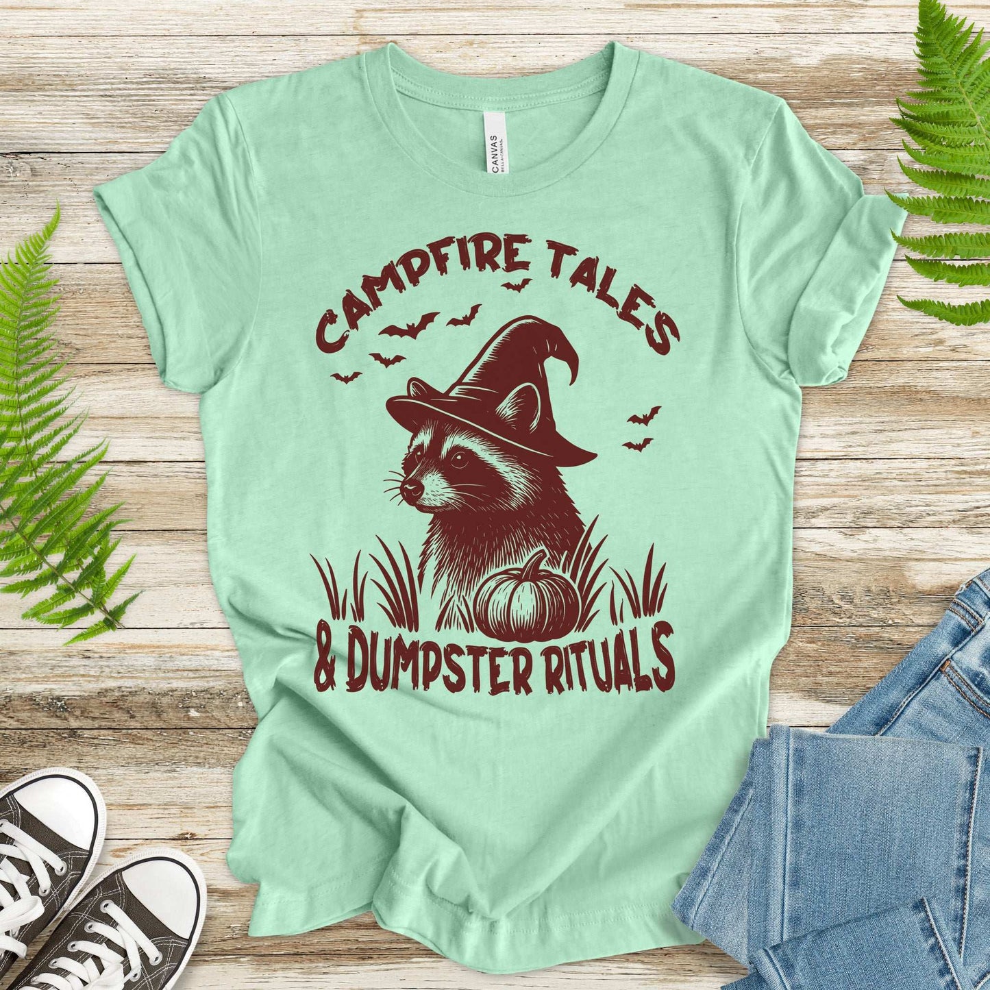 Campfire Tales Raccoon Halloween T-shirt featuring a witchy raccoon and pumpkin, perfect for spooky vibes.