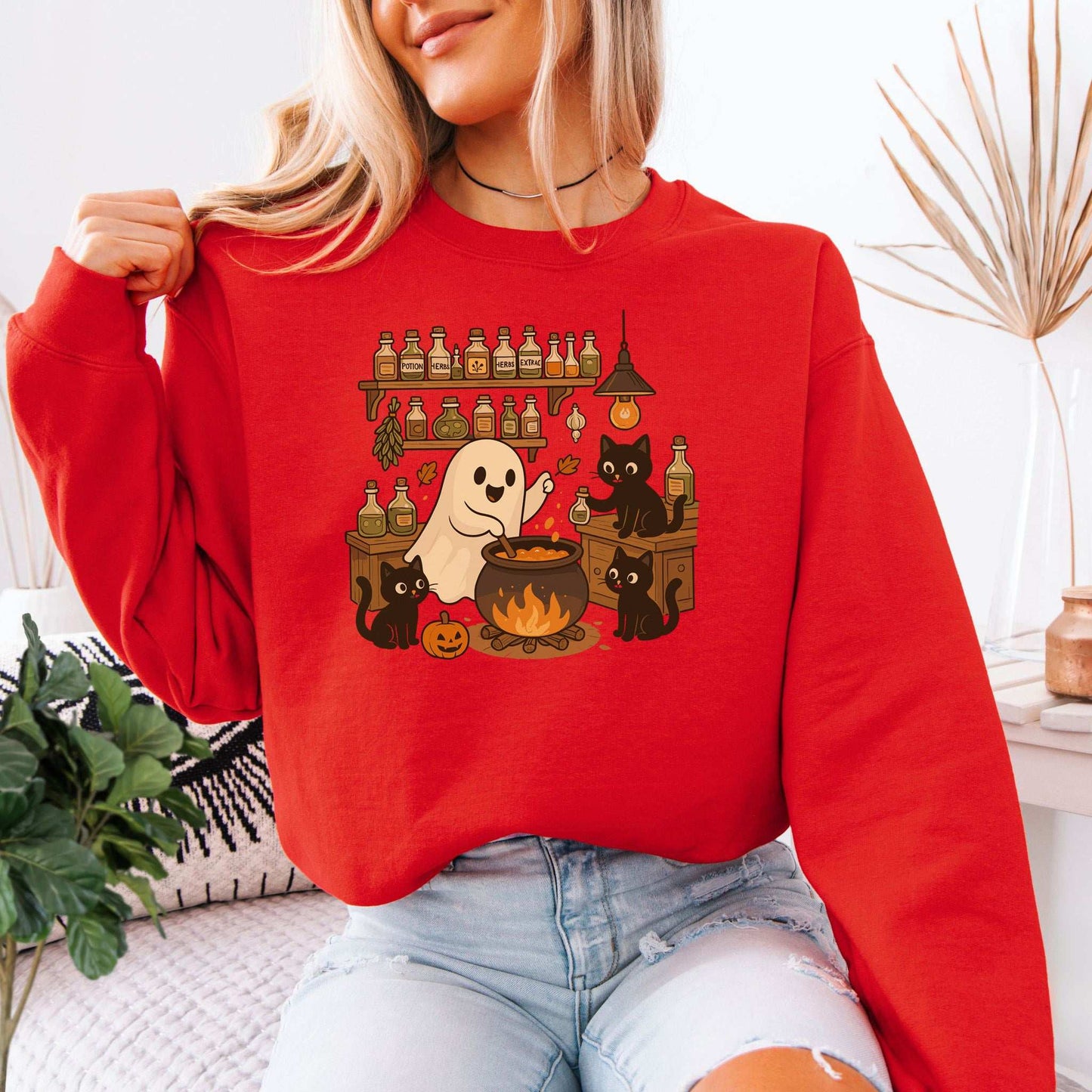 Ghost & Black Cats Cooking Halloween Sweatshirt featuring a cute ghost and black cats in a cozy kitchen setting.