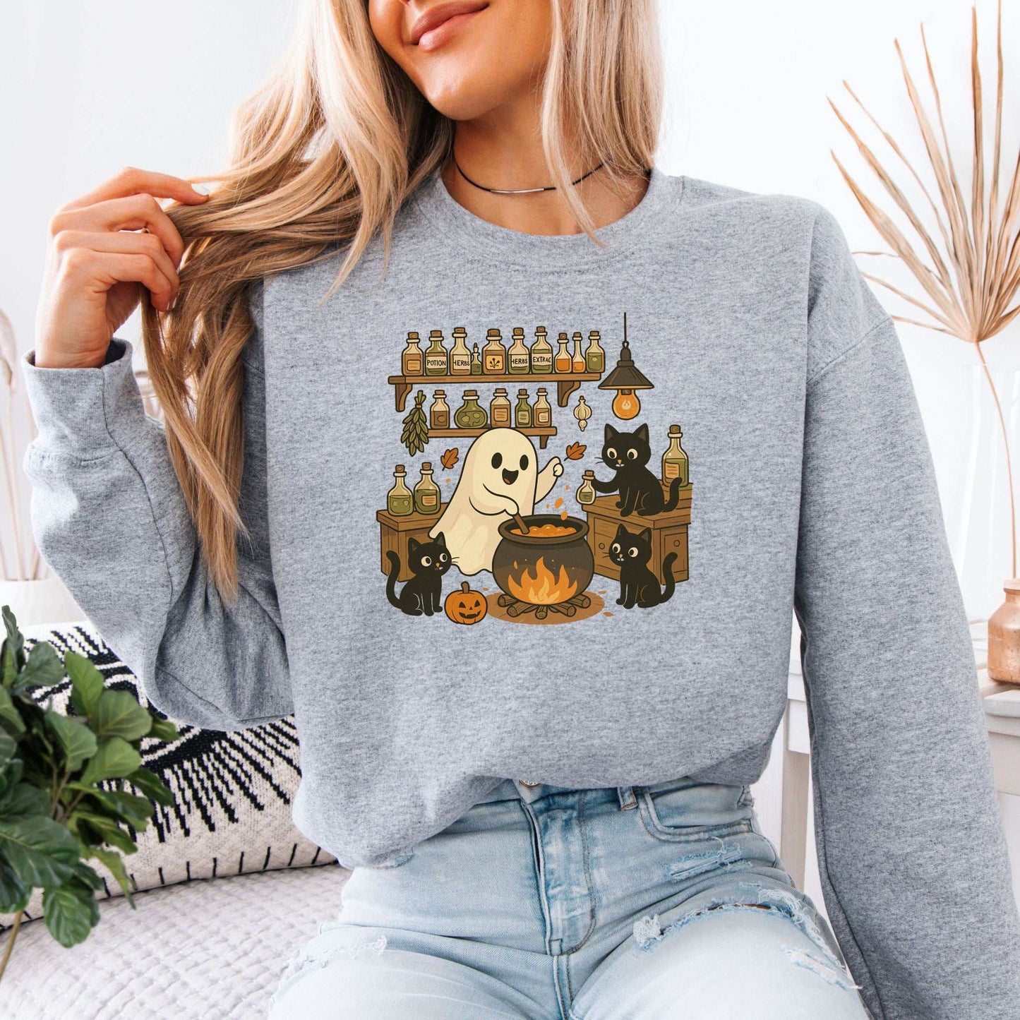Ghost & Black Cats Cooking Halloween Sweatshirt with a ghost and black cats making potions in a cozy kitchen setting.