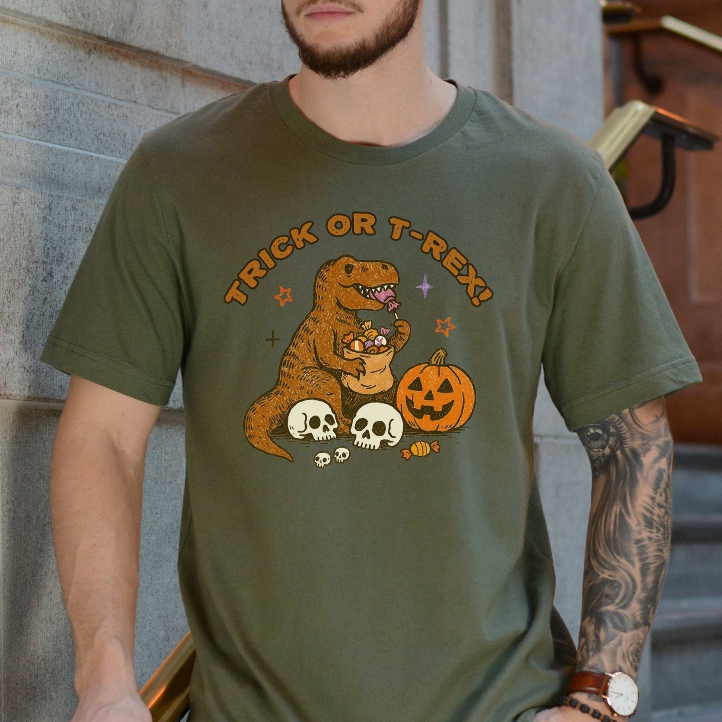 T-Rex Halloween T-Shirt featuring a dino hoarding candy with pumpkins and skulls, perfect for Trick or Treat vibes.