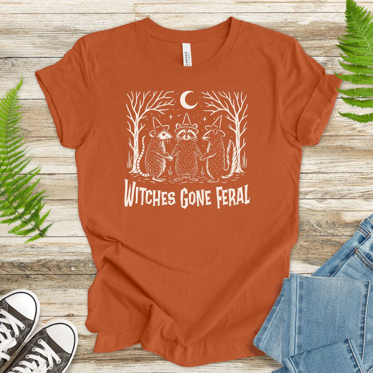 Witches Gone Feral Halloween T-Shirt featuring raccoon, opossum, and skunk under a crescent moon.