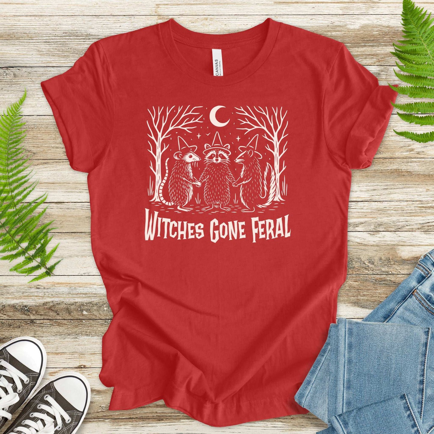 Witches Gone Feral Halloween T-shirt featuring raccoon, opossum, and skunk under a crescent moon.