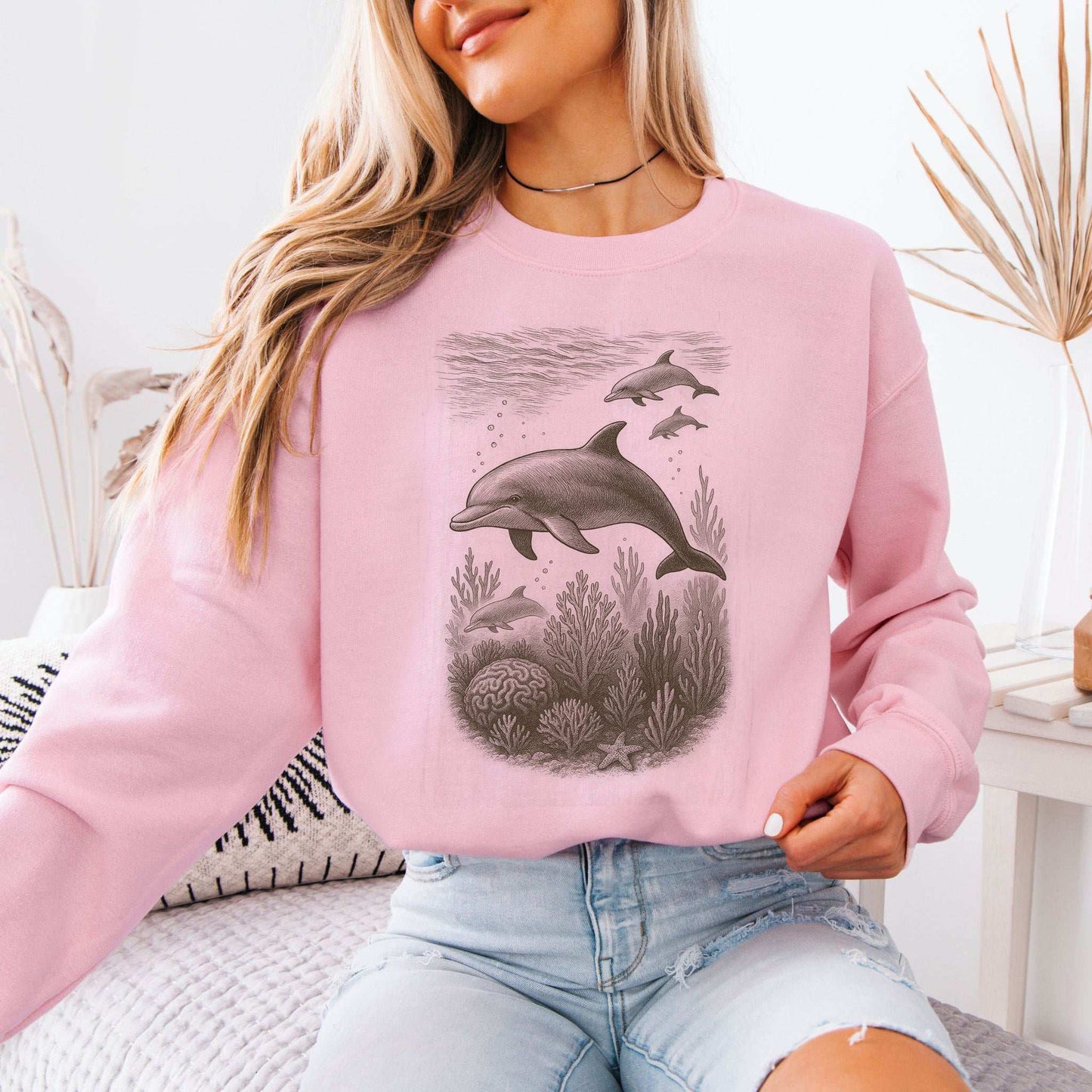 Dolphins and coral reef sketch on a cozy pink sweatshirt, perfect for ocean spirit animal lovers.