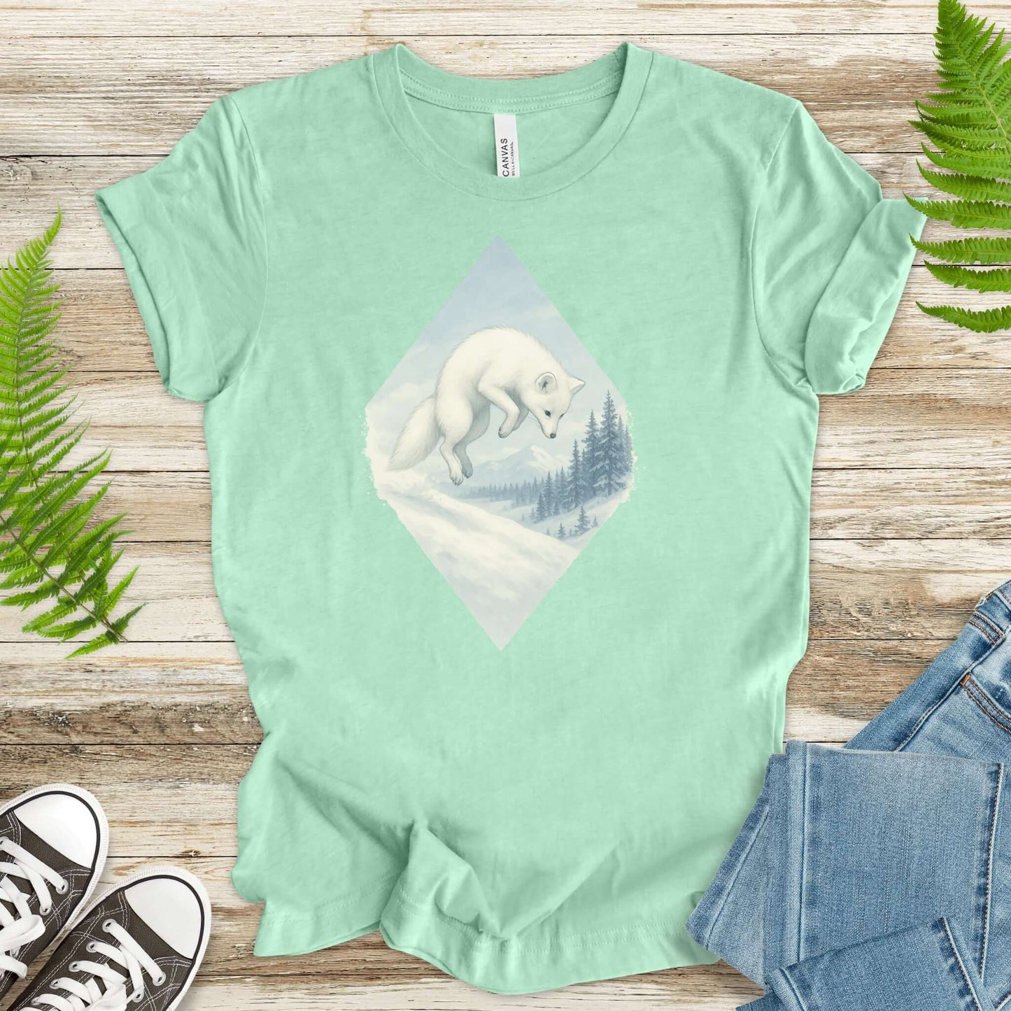 Jumping white fox graphic on mint shirt, perfect for fantasy lovers and animal enthusiasts.