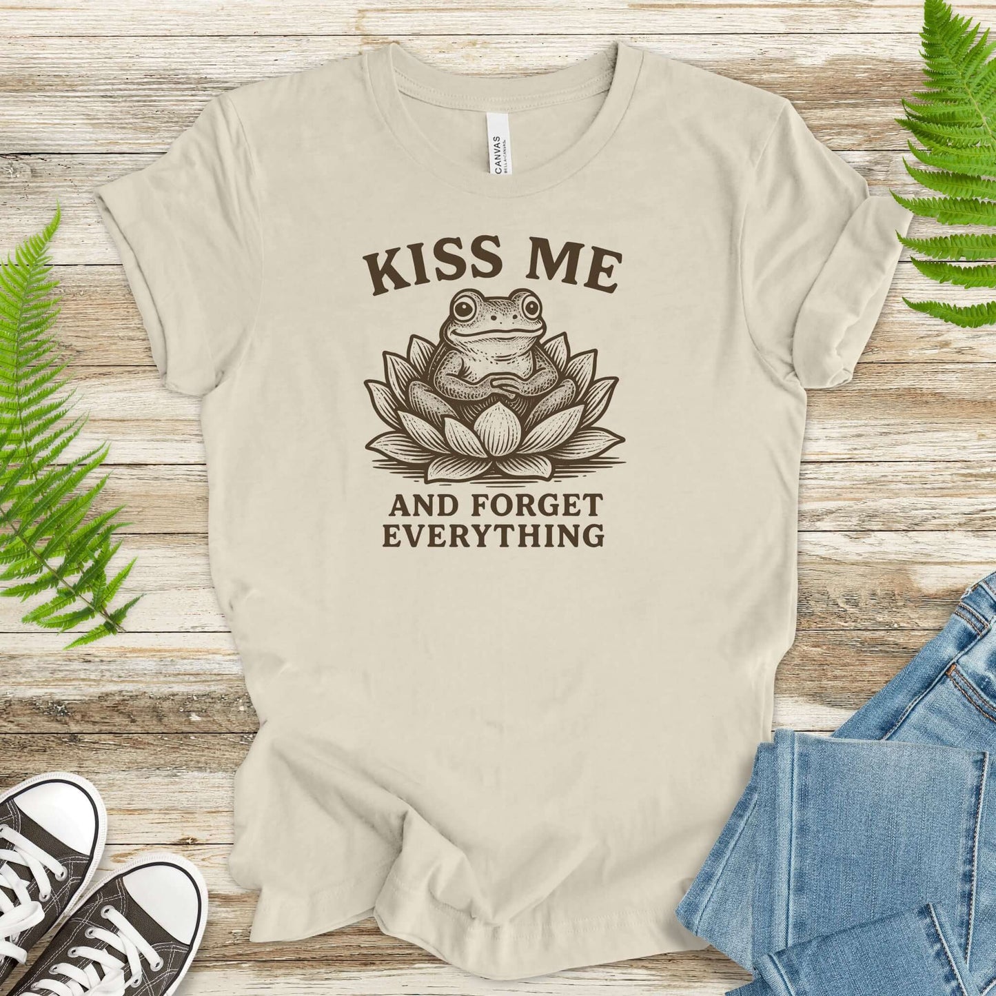 Funny frog in lotus flower tee saying 'Kiss Me and Forget Everything' for a whimsical touch.