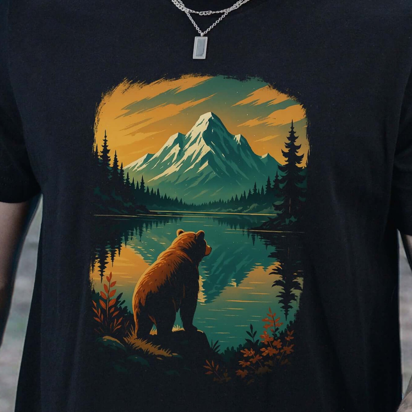 Person wearing a black t-shirt with a bear and mountain design in a forest setting.