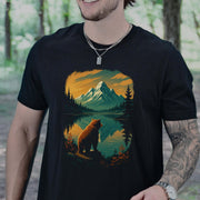 Person wearing a black t-shirt with a bear and mountain design in a forest setting.