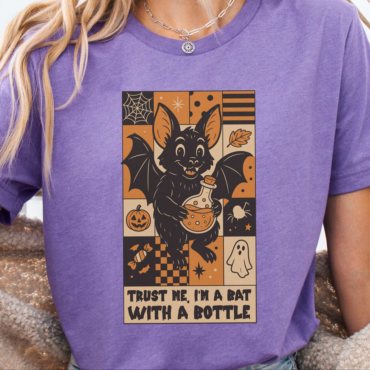 Woman wearing a Heather Team Purple T-shirt printed with a bat holding a potion bottle, retro illustration
