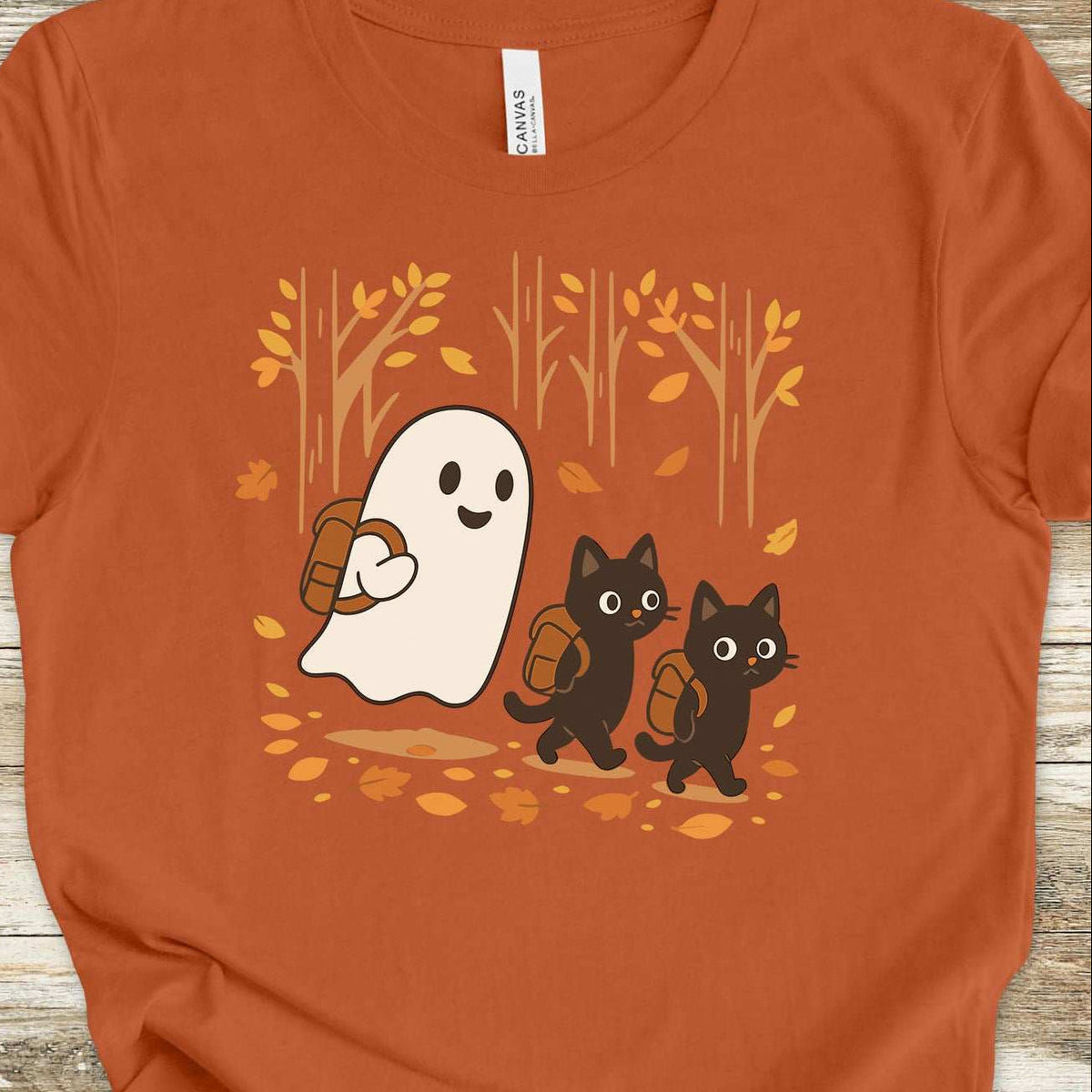 A ghost and black cats hiking through fall leaves design on an Autumn T-shirt