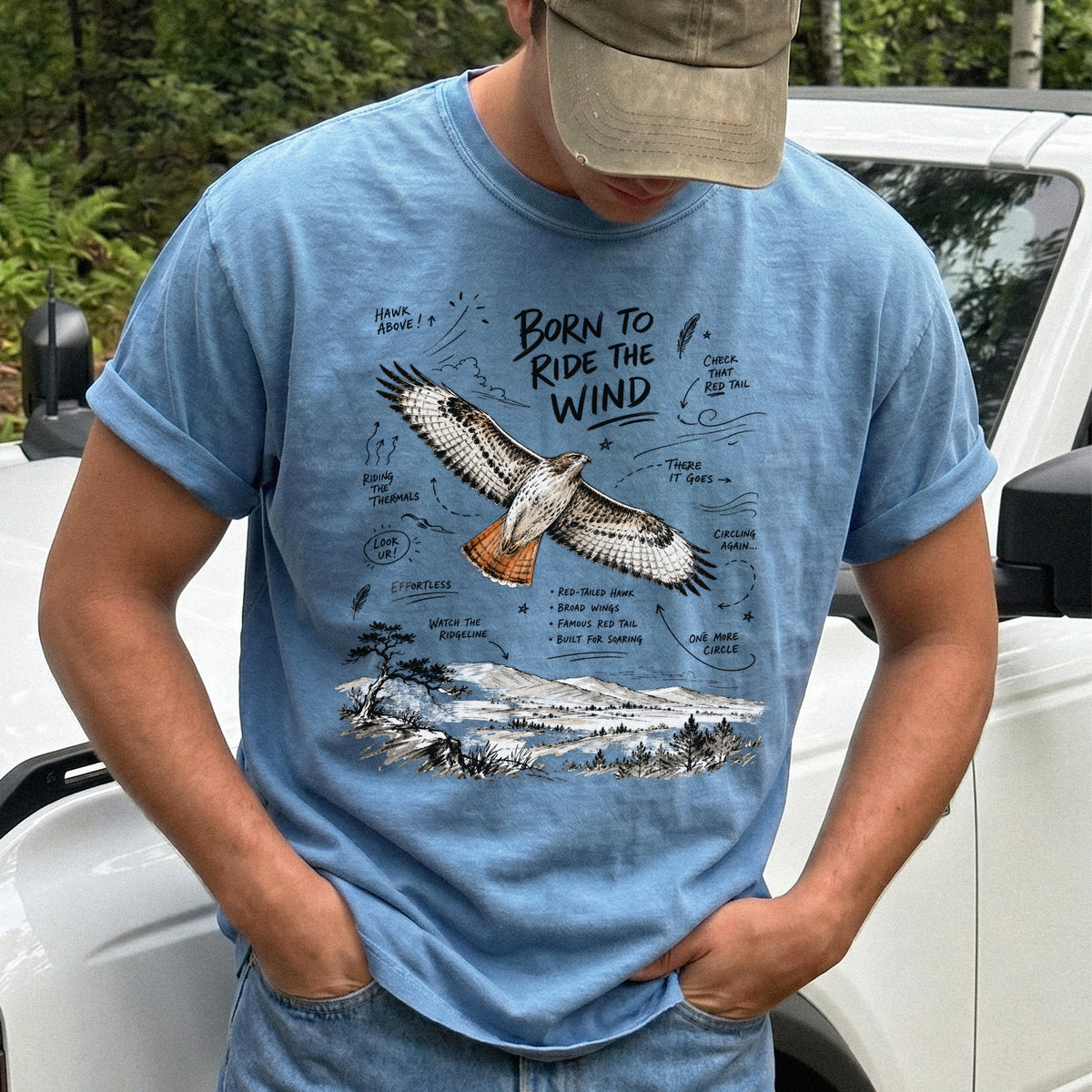 Born to Ride the Wind Comfort Colors Shirt – Red-Tailed Hawk design of a Red-Tailed Hawk illustrated in flight above an open ridgeline, with field-note style callouts and a scenic landscape below, printed on a Blue Jean T-shirt.