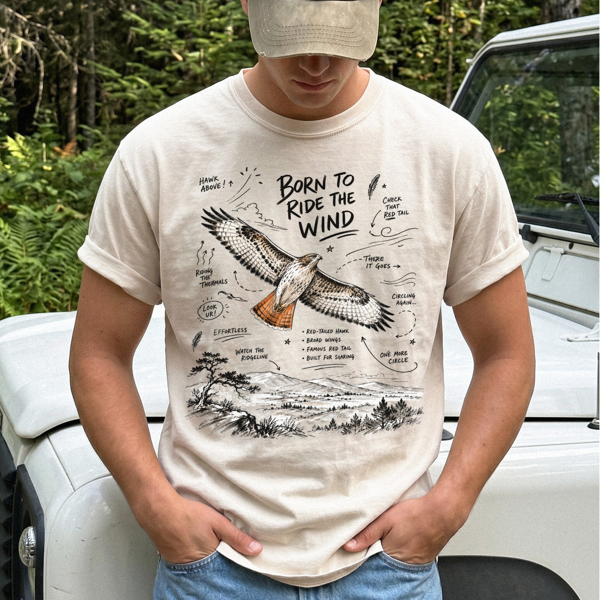 Born to Ride the Wind Comfort Colors Shirt – Red-Tailed Hawk design of a Red-Tailed Hawk illustrated in flight above an open ridgeline, with field-note style callouts and a scenic landscape below, printed on an Ivory T-shirt.