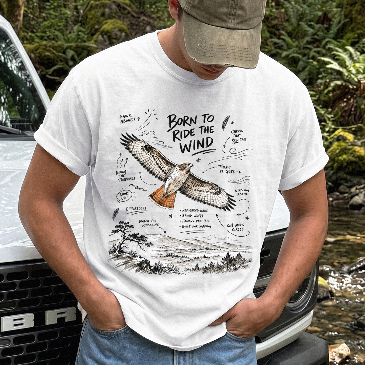 Born to Ride the Wind Comfort Colors Shirt – Red-Tailed Hawk design of a Red-Tailed Hawk illustrated in flight above an open ridgeline, with field-note style callouts and a scenic landscape below, printed on a White T-shirt.
