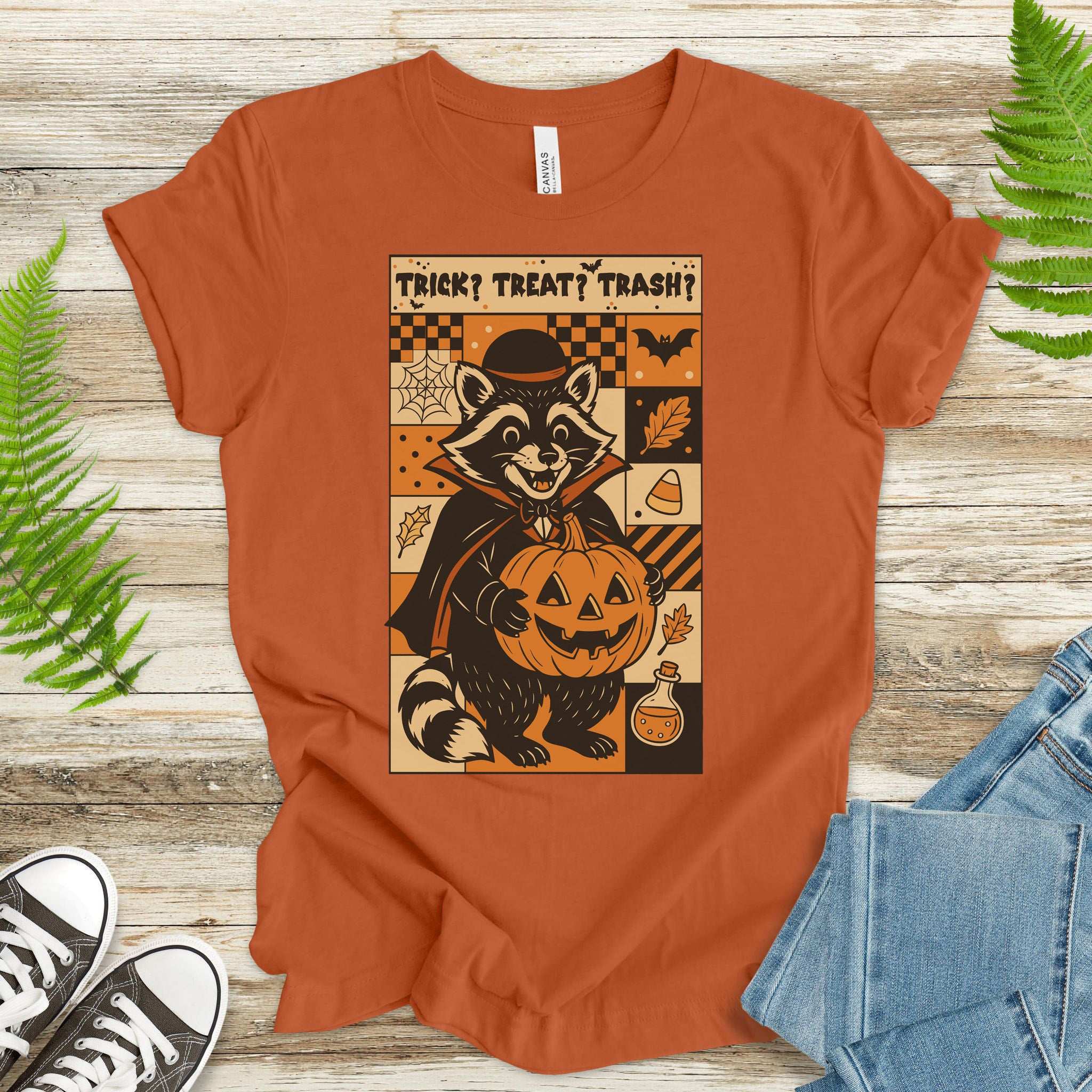 Dracula Raccoon Halloween T-shirt featuring a playful raccoon in a cape with a pumpkin, perfect for spooky celebrations.