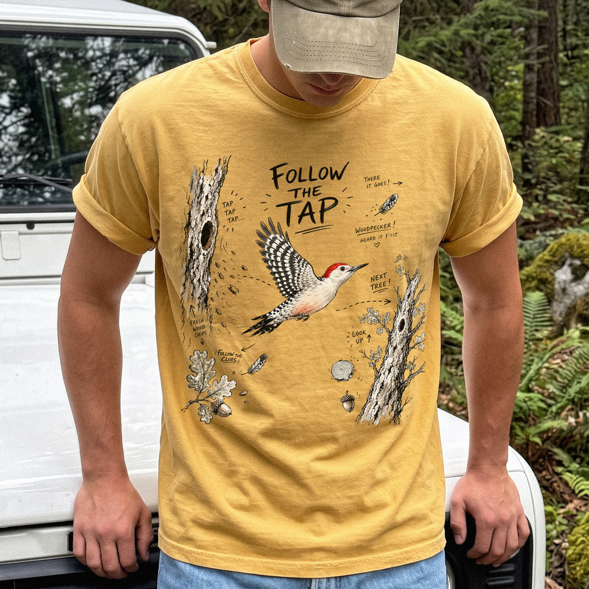 Follow the Tap Comfort Colors Shirt – Red-Bellied Woodpecker design of a Red-Bellied Woodpecker illustrated in flight, surrounded by tree trunks, wood chips, feathers, oak leaves, and acorn details, printed on a Mustard T-shirt.