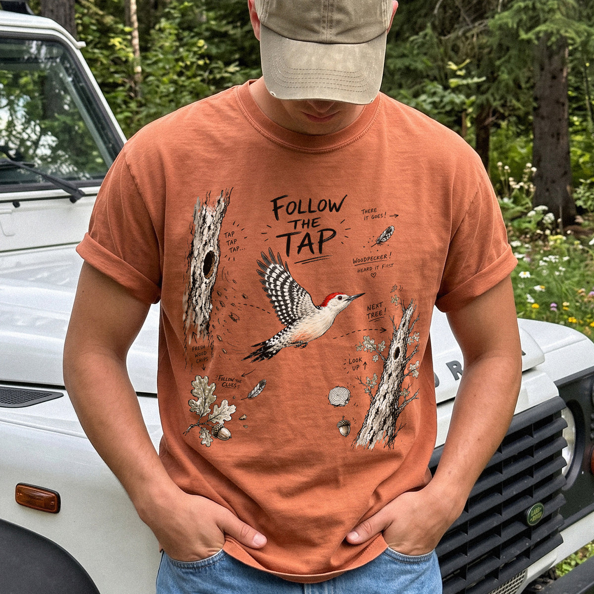 Follow the Tap Comfort Colors Shirt – Red-Bellied Woodpecker design of a Red-Bellied Woodpecker illustrated in flight, surrounded by tree trunks, wood chips, feathers, oak leaves, and acorn details, printed on a Yam T-shirt.