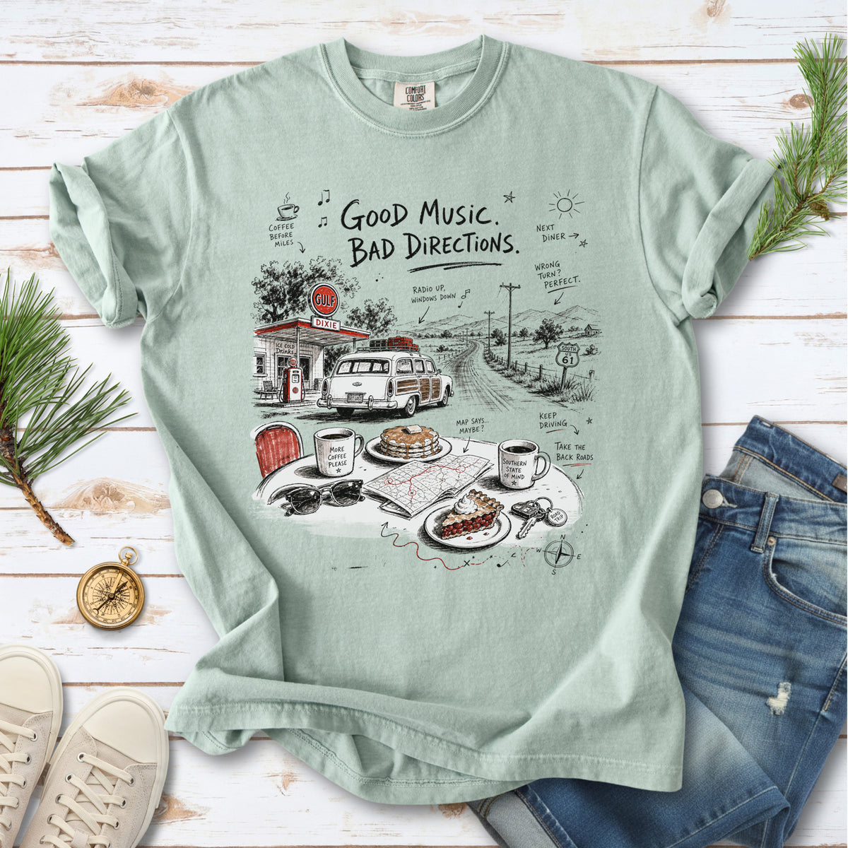 A vintage roadside scene with a classic car, old gas station, and a winding back road design on a Bay Comfort Colors T-shirt