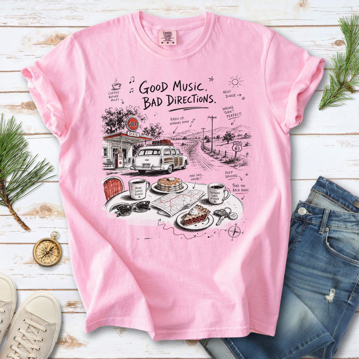 A vintage roadside scene with a classic car, old gas station, and a winding back road design on a Blossom Comfort Colors T-shirt