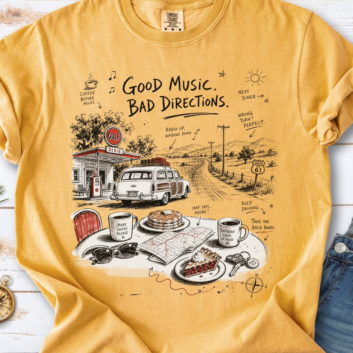 A vintage roadside scene with a classic car, old gas station, and a winding back road design on a Mustard Comfort Colors T-shirt