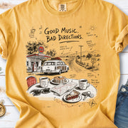 A vintage roadside scene with a classic car, old gas station, and a winding back road design on a Mustard Comfort Colors T-shirt