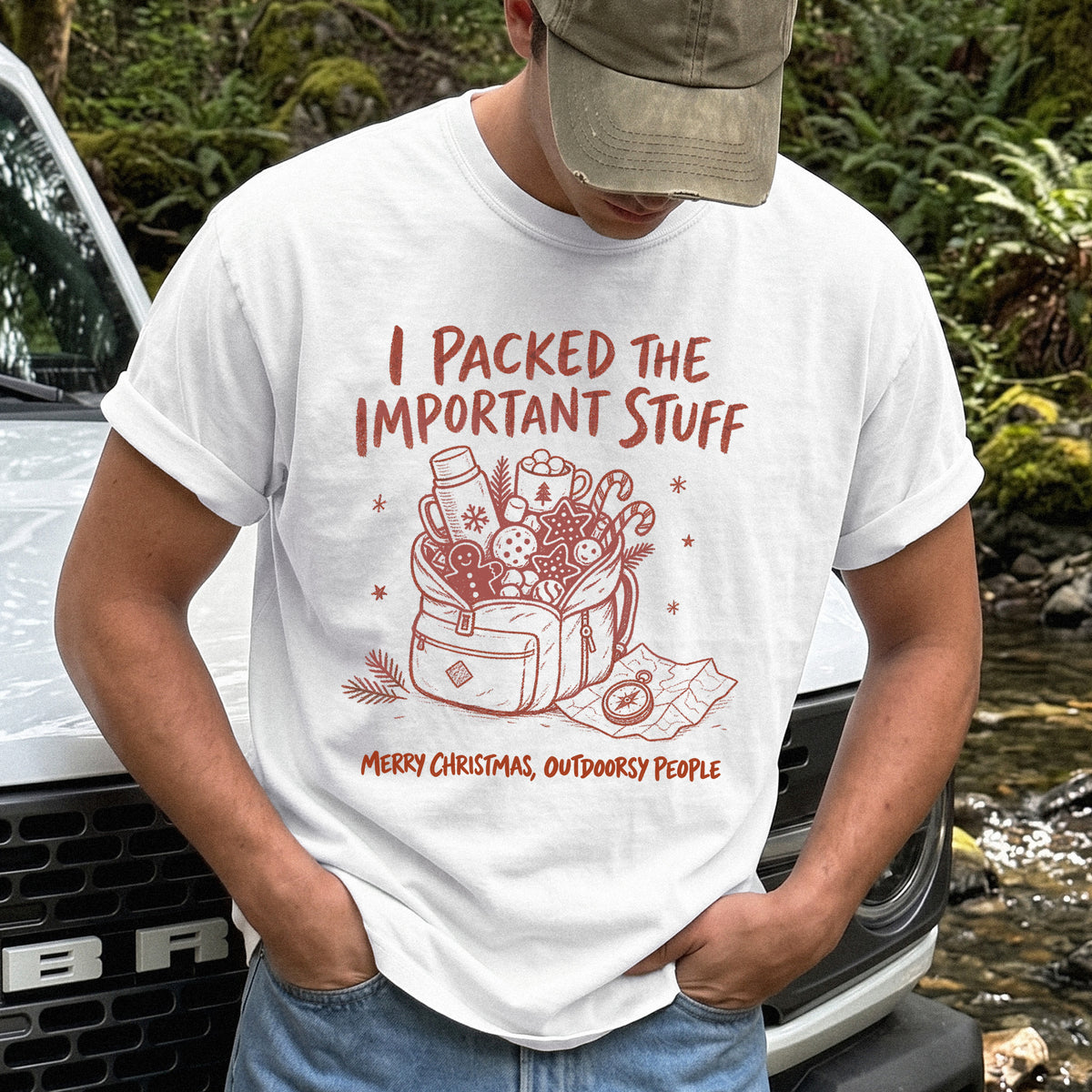 Man wearing a White T-shirt printed with an overstuffed backpack with a thermos, mug, compass, trail map, and festive treats, doodle style