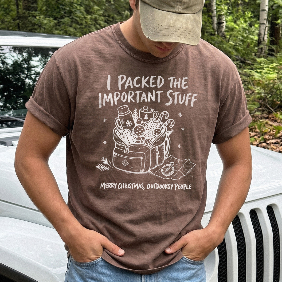 Man wearing an Espresso T-shirt printed with an overstuffed backpack with a thermos, mug, compass, trail map, and festive treats, doodle style