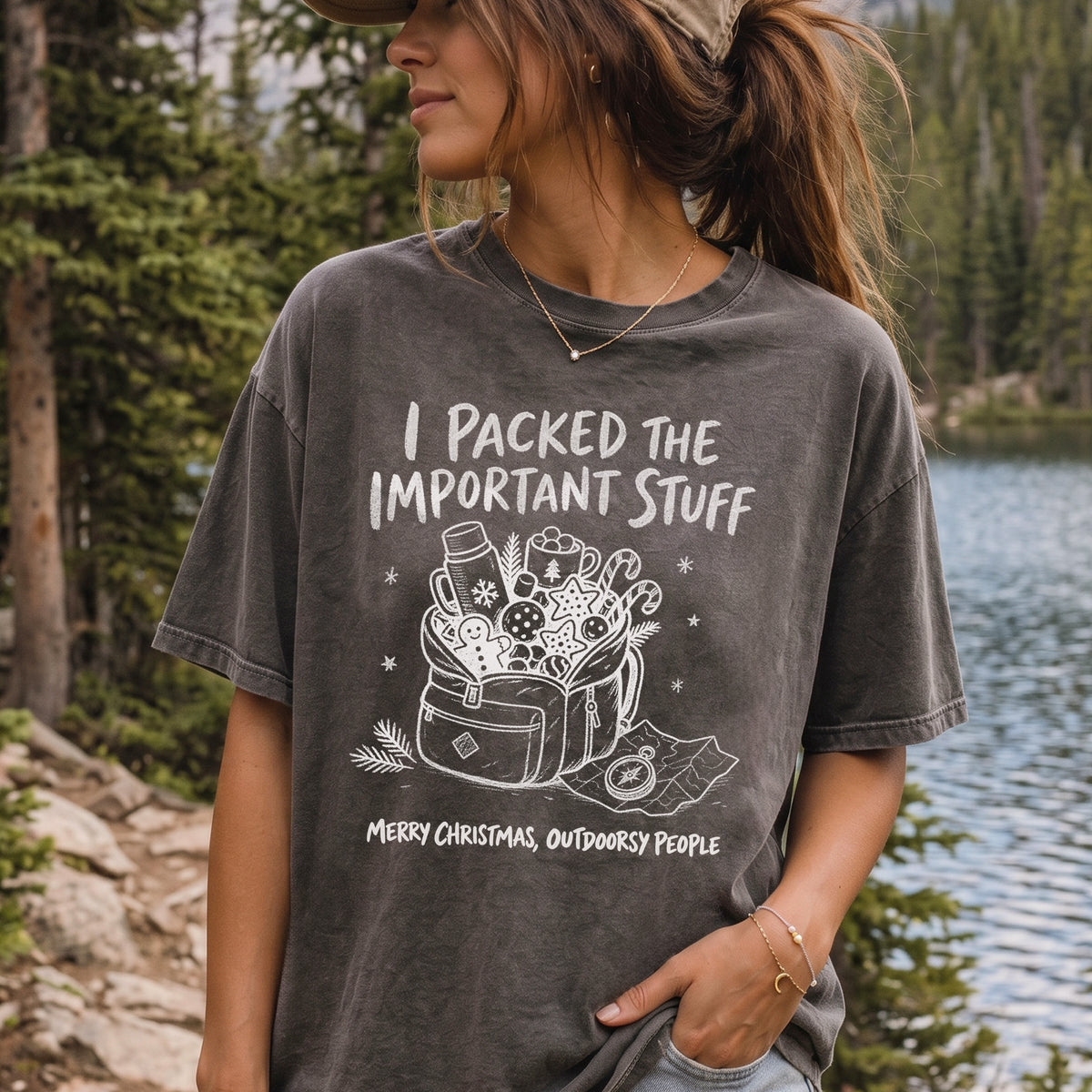 Woman wearing a Pepper T-shirt printed with an overstuffed backpack with a thermos, mug, compass, trail map, and festive treats, doodle style