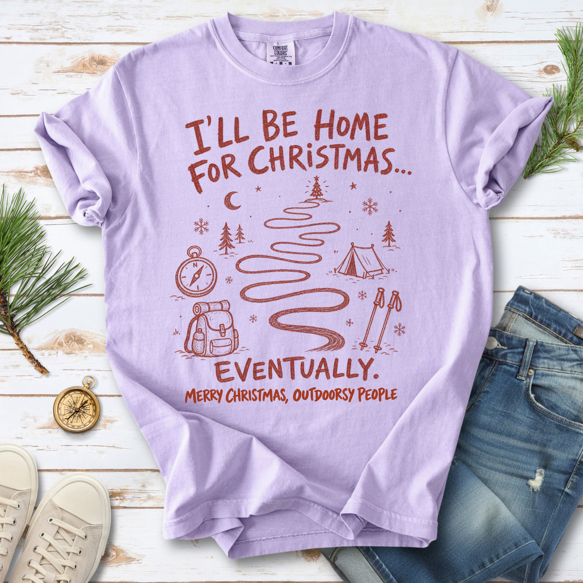 A winding trail with a tent, compass, backpack, trekking poles, snowflakes, and pine trees, doodle style design on an Orchid T-shirt