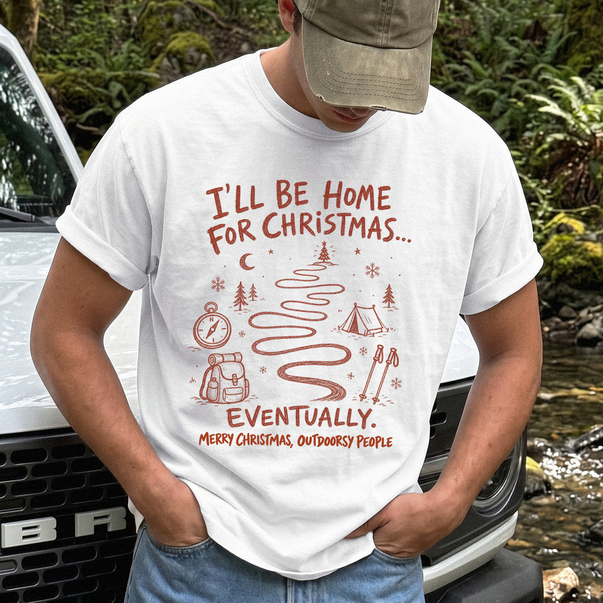 Man wearing a White T-shirt printed with a winding trail with a tent, compass, backpack, trekking poles, snowflakes, and pine trees, doodle style