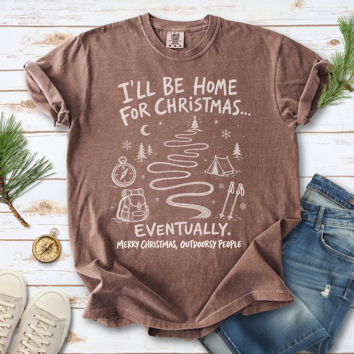 A winding trail with a tent, compass, backpack, trekking poles, snowflakes, and pine trees, doodle style design on an Espresso T-shirt