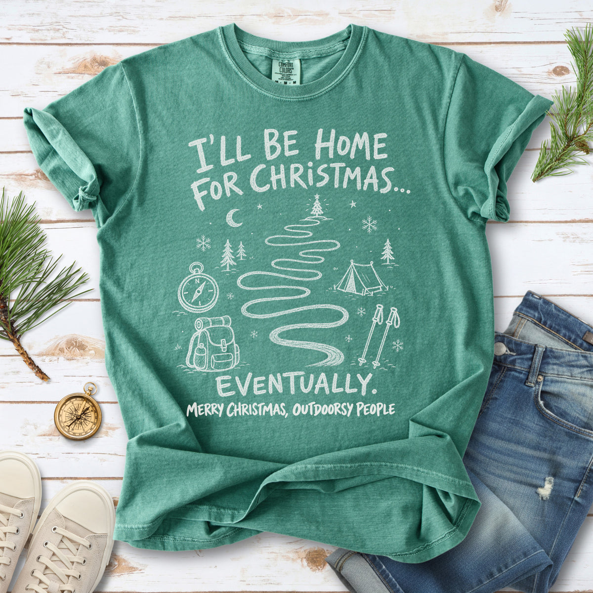 A winding trail with a tent, compass, backpack, trekking poles, snowflakes, and pine trees, doodle style design on a Light Green T-shirt