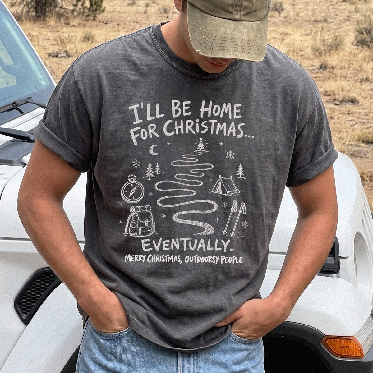 Man wearing a Pepper T-shirt printed with a winding trail with a tent, compass, backpack, trekking poles, snowflakes, and pine trees, doodle style