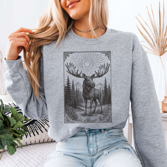 Woman wearing a Mystic Moose Crewneck, featuring a bull moose design surrounded by forest and mountains.