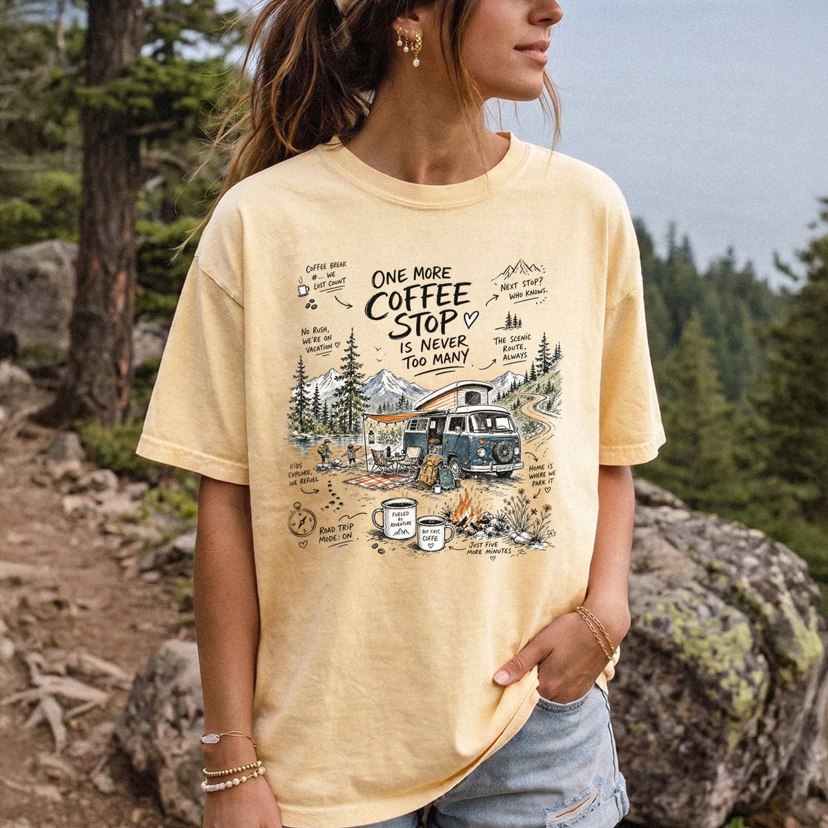 Woman wearing a Butter Comfort Colors T-shirt printed with a retro camper van parked by the water with mountain views and camp chairs