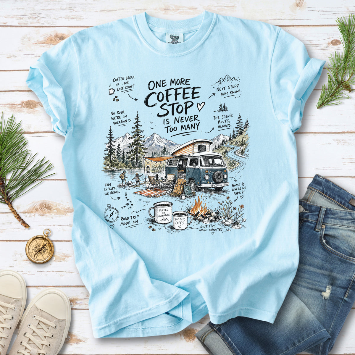 A retro camper van parked by the water with mountain views and camp chairs design on a Chambray Comfort Colors T-shirt