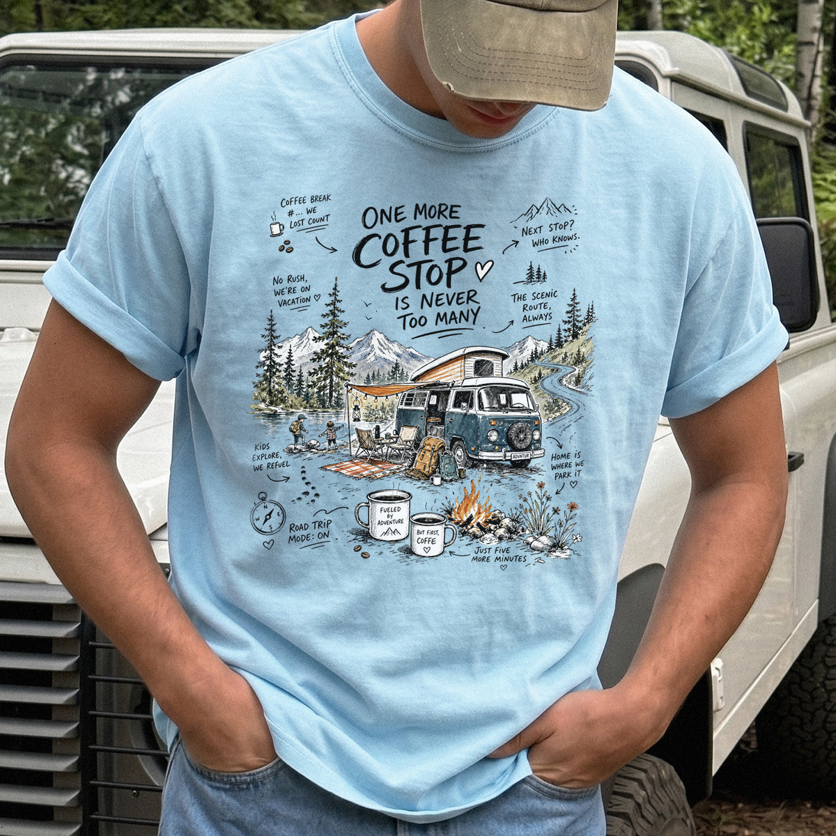 Man wearing a Chambray Comfort Colors T-shirt with a retro camper van parked by the water with mountain views and camp chairs