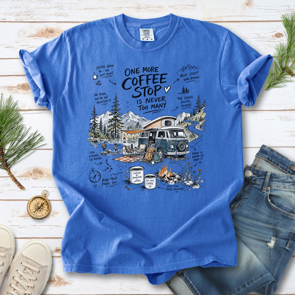 A retro camper van parked by the water with mountain views and camp chairs design on a Flo Blue Comfort Colors T-shirt