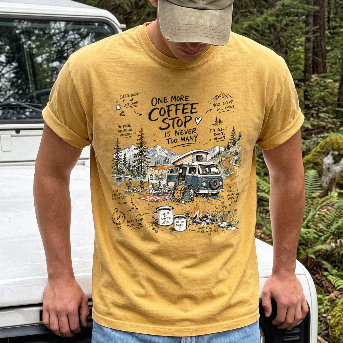 Man wearing a Mustard Comfort Colors T-shirt with a retro camper van parked by the water with mountain views and camp chairs