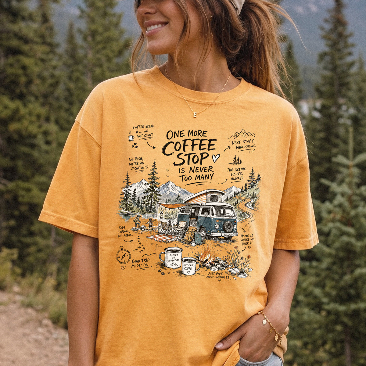 Woman wearing a Mustard Comfort Colors T-shirt printed with a retro camper van parked by the water with mountain views and camp chairs