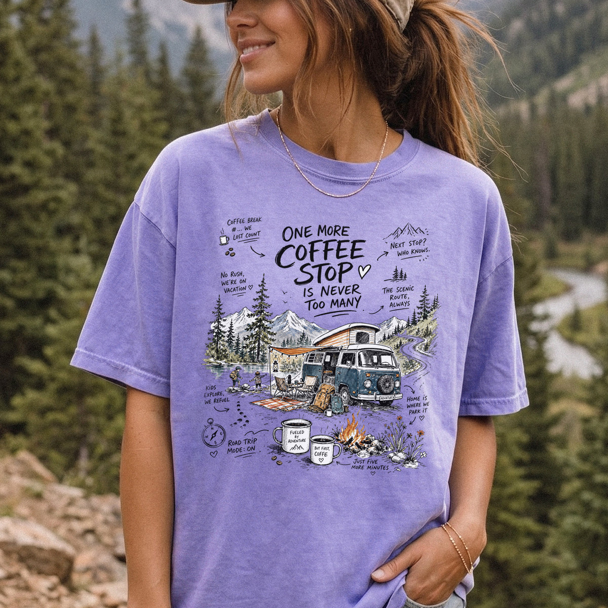 Woman wearing a Violet Comfort Colors T-shirt printed with a retro camper van parked by the water with mountain views and camp chairs