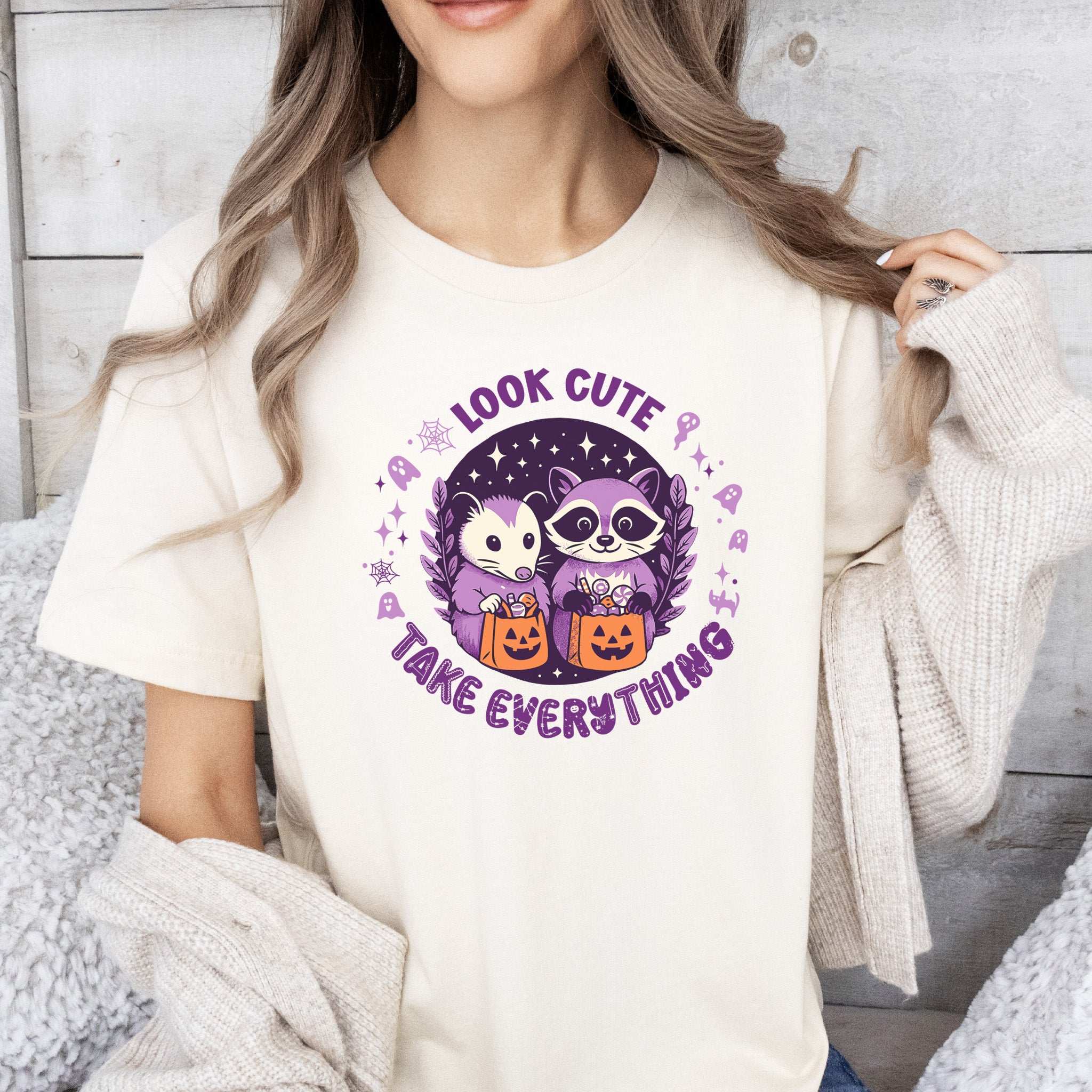 Opossum & Raccoon Halloween T-shirt featuring 'Look Cute, Take Everything' design with candy buckets.