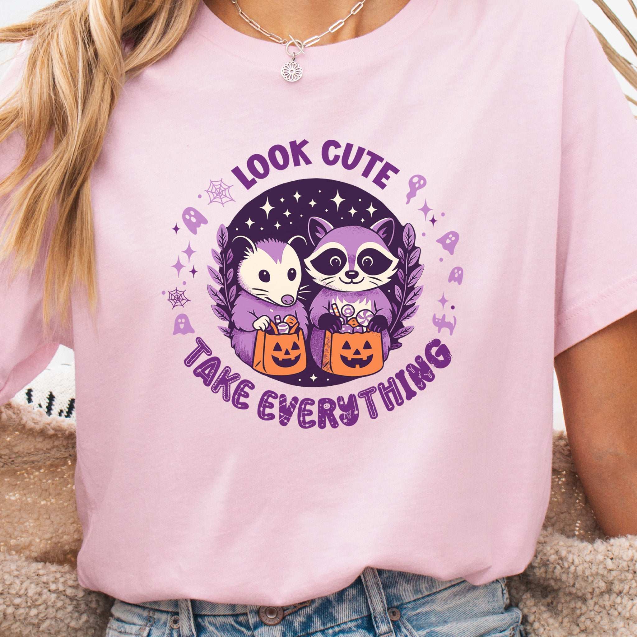 Opossum & Raccoon Halloween T-shirt with "Look Cute, Take Everything" design in pastel colors.