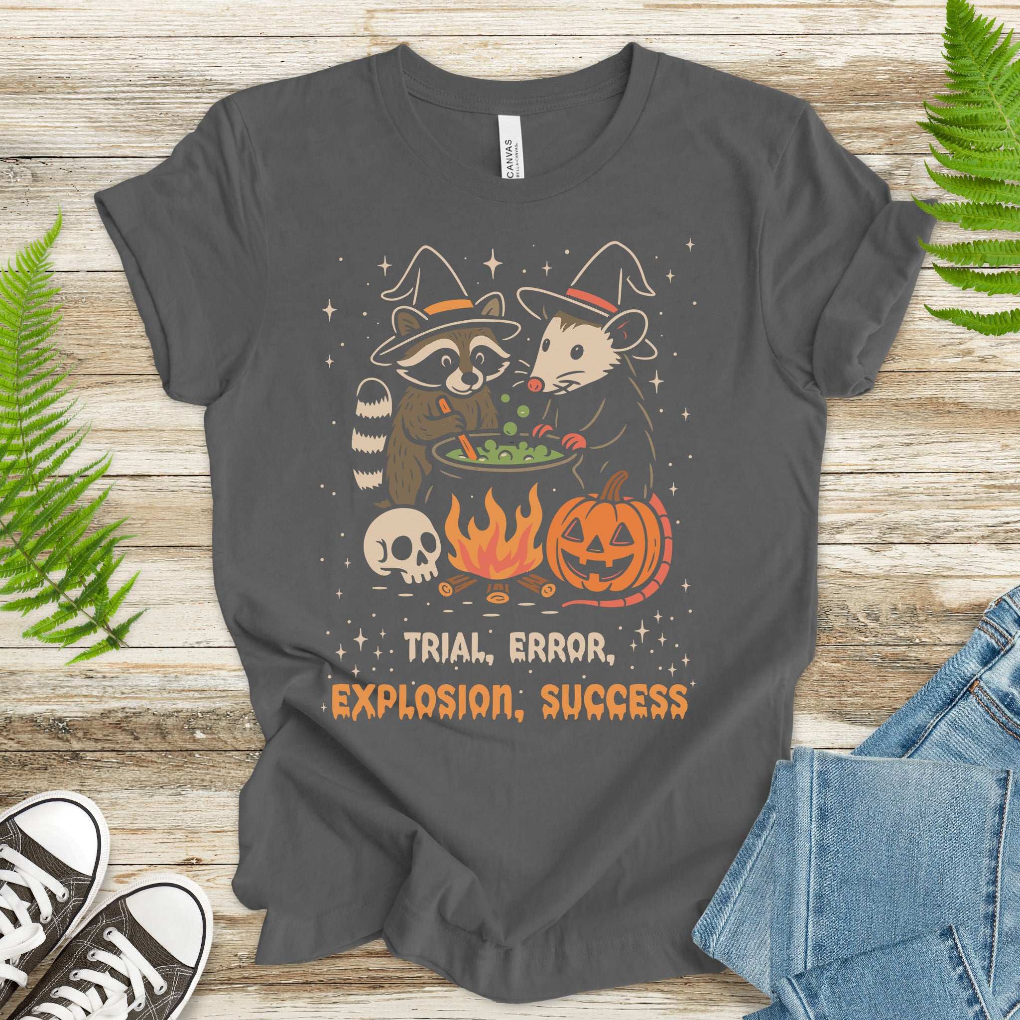 Potion Explosion Halloween T-shirt with raccoon and opossum in witch hats, featuring trial, error, explosion, success design.