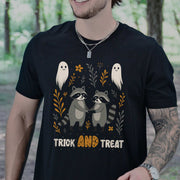 Man wearing Trick AND Treat Raccoon Halloween T-shirt with cute ghosts and woodland design in a forest setting.