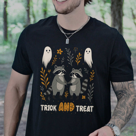 Man wearing Trick AND Treat Raccoon Halloween T-shirt with cute ghosts and woodland design in a forest setting.