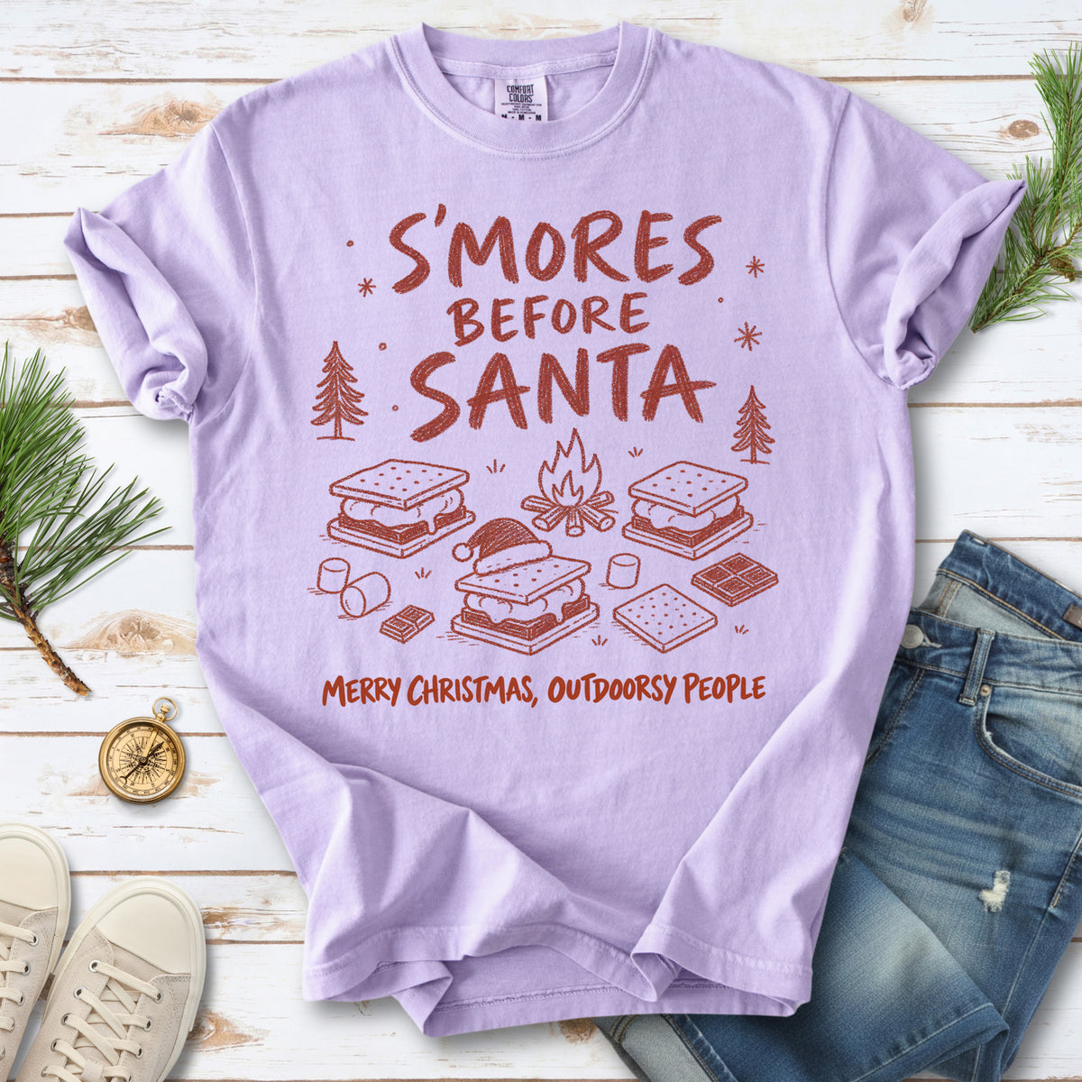 S’mores, a crackling campfire, marshmallows, chocolate pieces, pine trees, and a tiny Santa hat, doodle style design on an Orchid T-shirt