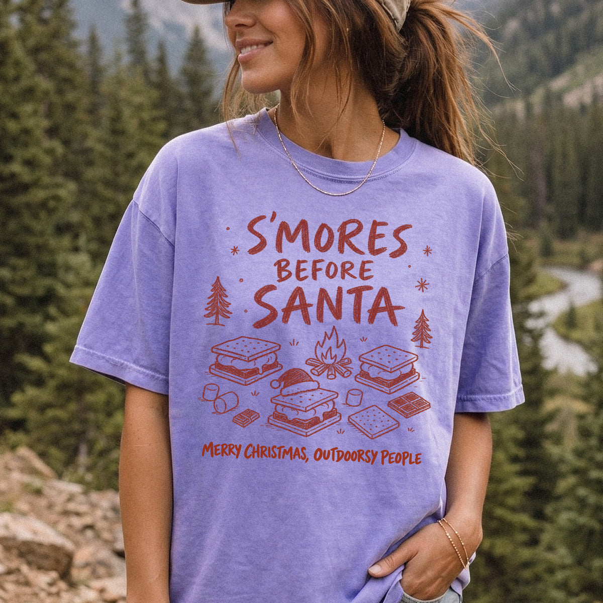 Woman wearing a Violet T-shirt printed with s’mores, a crackling campfire, marshmallows, chocolate pieces, pine trees, and a tiny Santa hat, doodle style