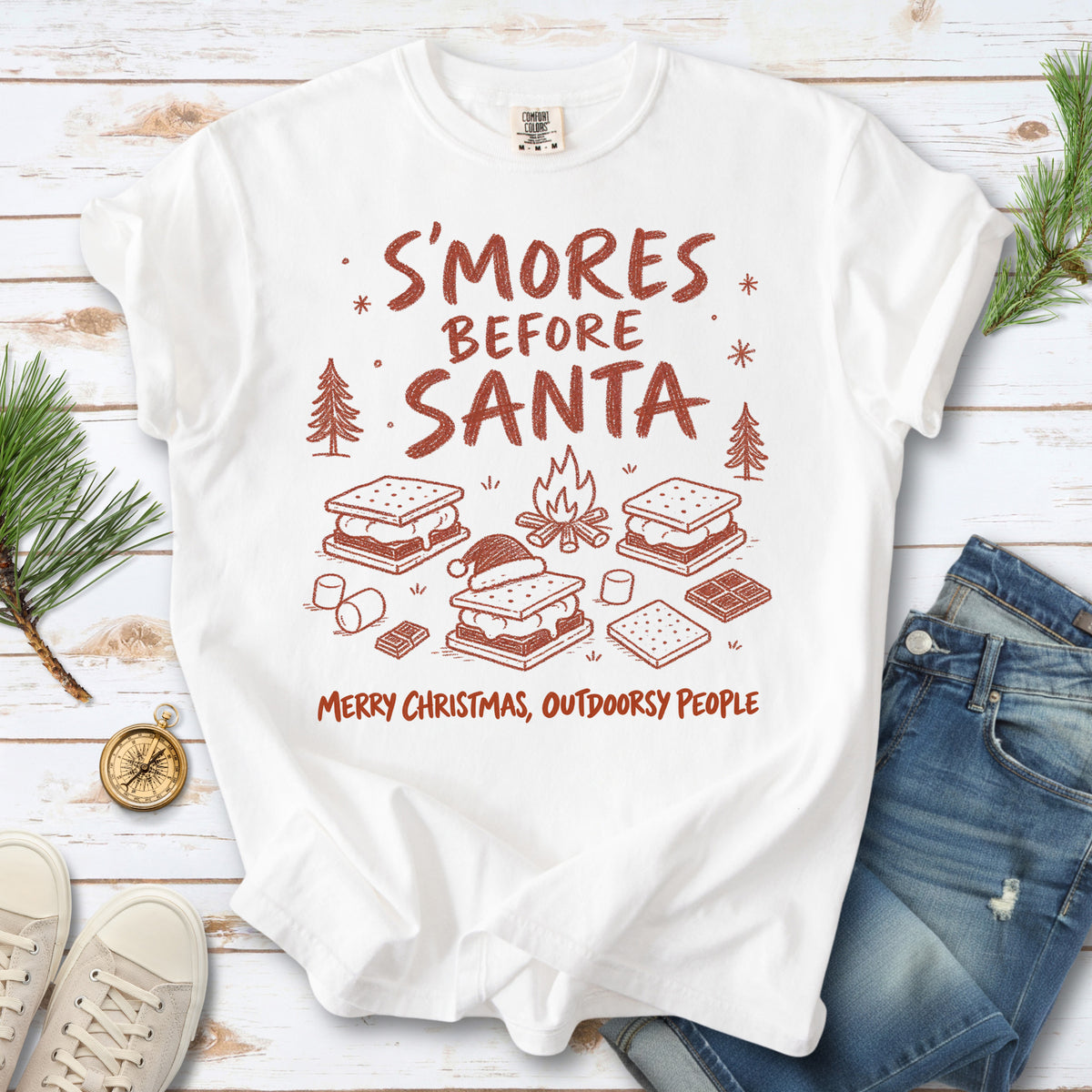S’mores, a crackling campfire, marshmallows, chocolate pieces, pine trees, and a tiny Santa hat, doodle style design on a White T-shirt