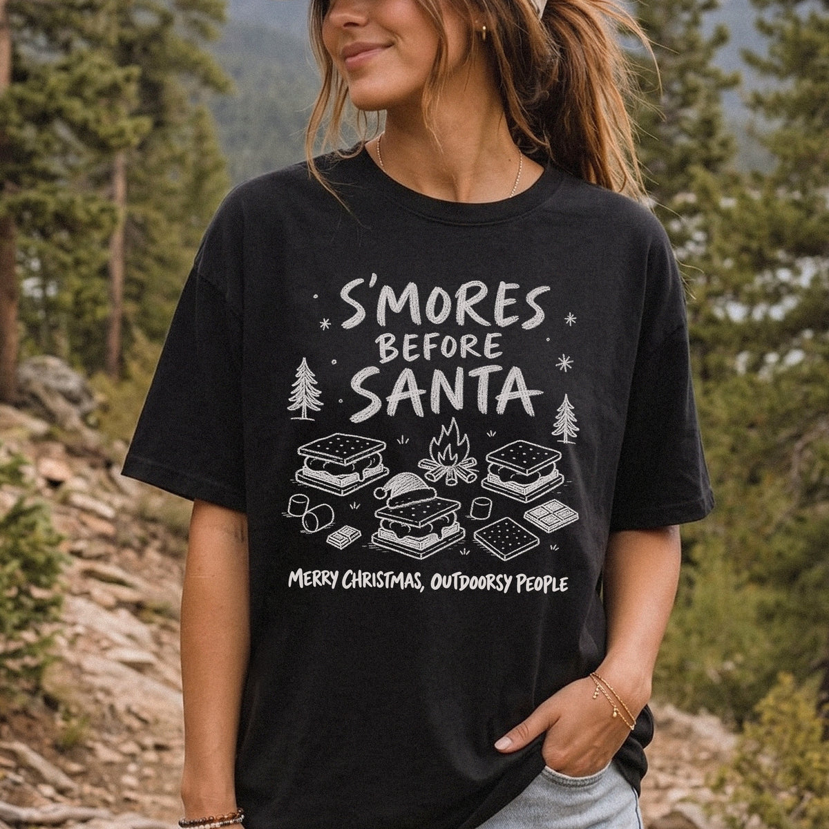 Woman wearing a Black T-shirt printed with s’mores, a crackling campfire, marshmallows, chocolate pieces, pine trees, and a tiny Santa hat, doodle style
