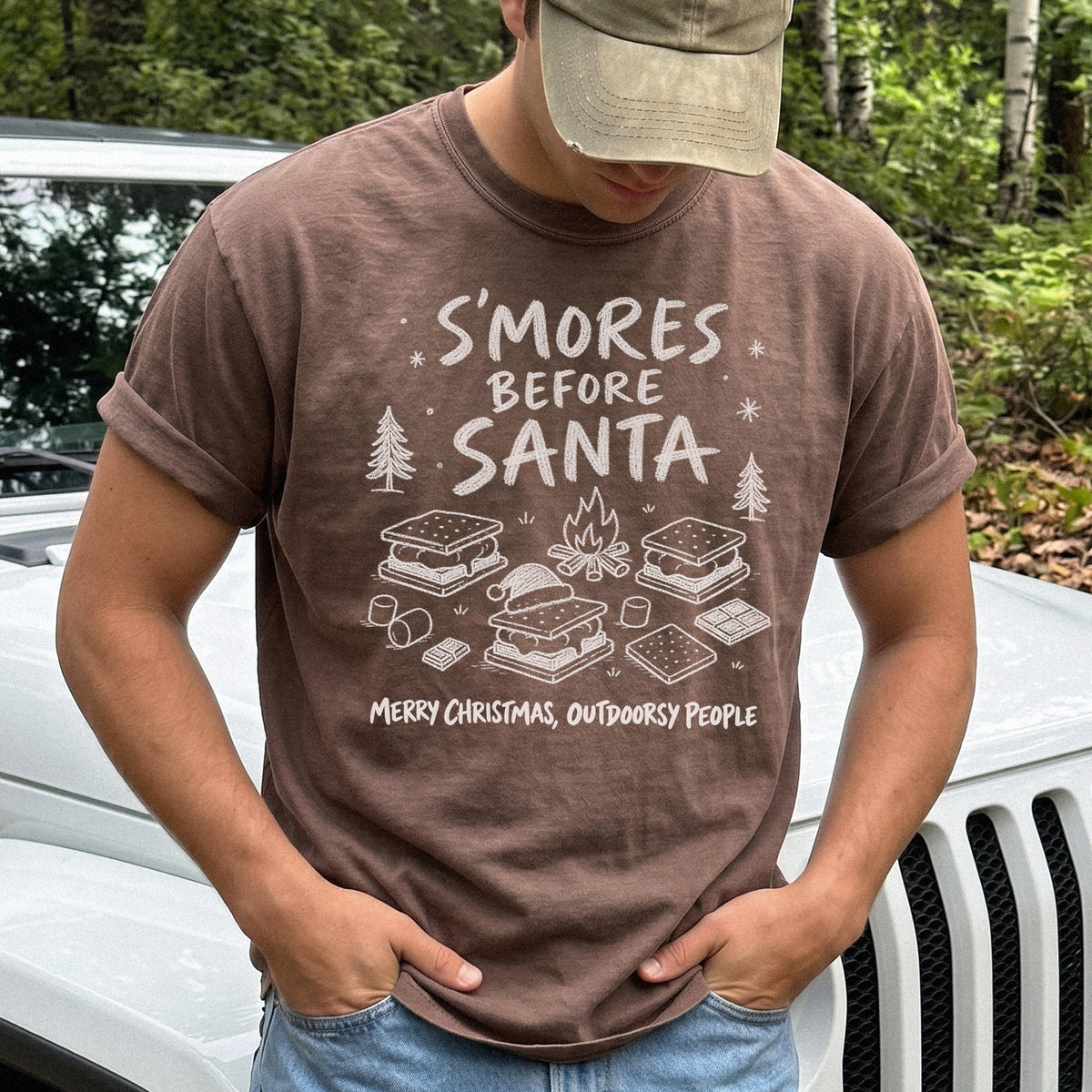 Man wearing an Espresso T-shirt printed with s’mores, a crackling campfire, marshmallows, chocolate pieces, pine trees, and a tiny Santa hat, doodle style