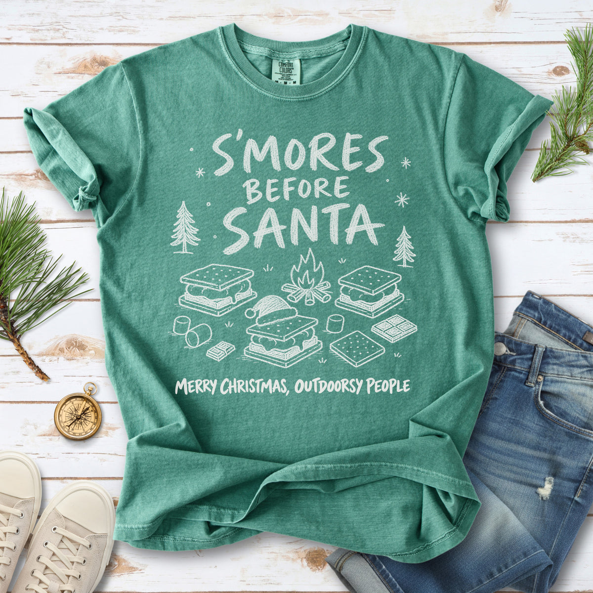 S’mores, a crackling campfire, marshmallows, chocolate pieces, pine trees, and a tiny Santa hat, doodle style design on a Light Green T-shirt